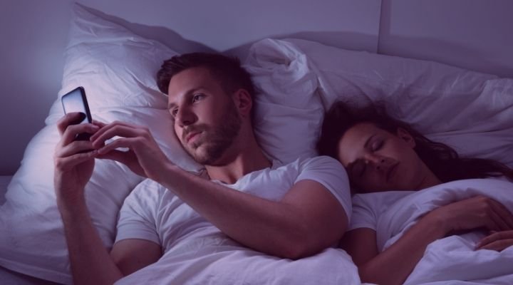 homem falando com a amante enquanto esposa dorme